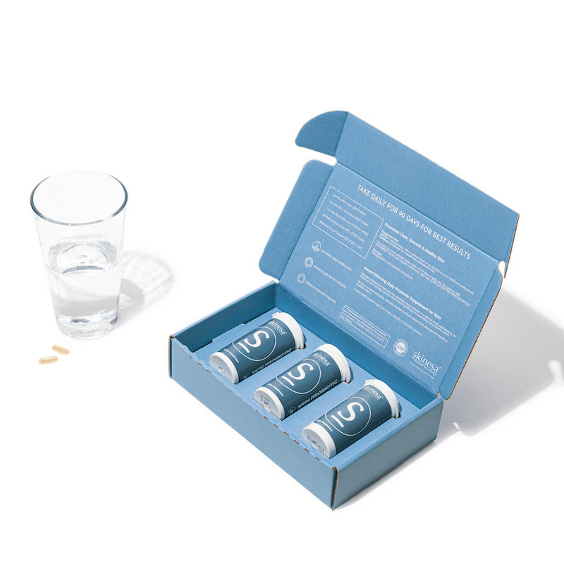 three bottles of skinesa and a glass of water with capsules