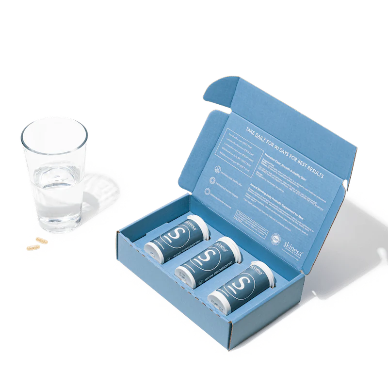 3 bottles of skinesa and a glass of water with capsules
